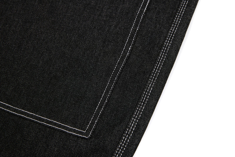 Close-up of black denim side seam with double topstitching and panel edge
