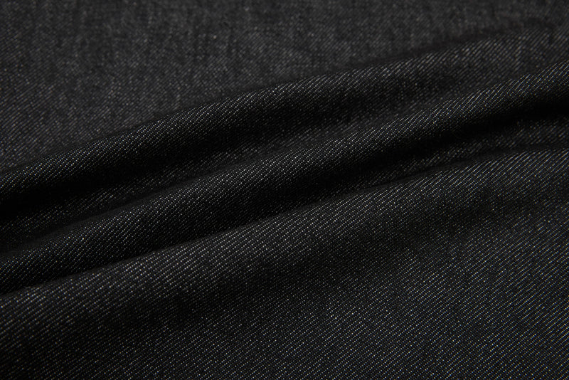 Close-up of black denim fabric texture with soft folds and visible weave