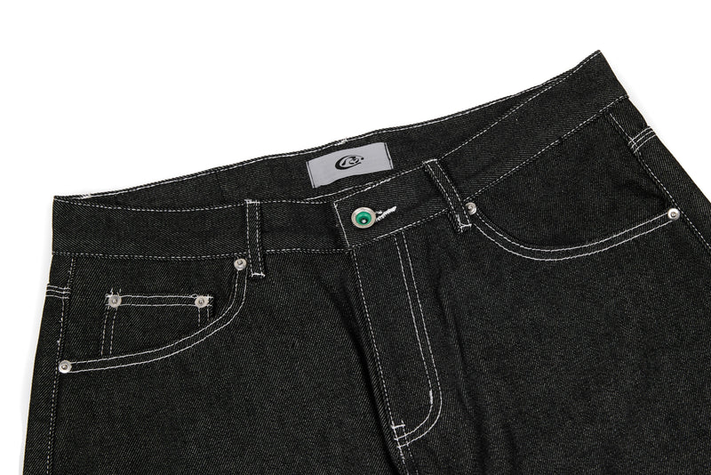 Close-up of black denim waistband and front pockets with contrast stitching and button
