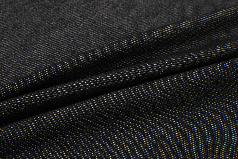 Close-up of black denim fabric showing diagonal twill texture and folds