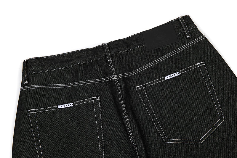 Back waistband of black denim jeans with stitched pockets and black patch label