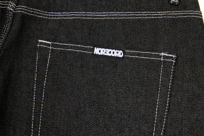 Back pocket close-up of black denim jeans with white logo tab and contrast stitching