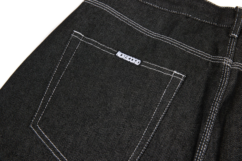 Back pocket close-up on black denim jeans with white stitched logo tab