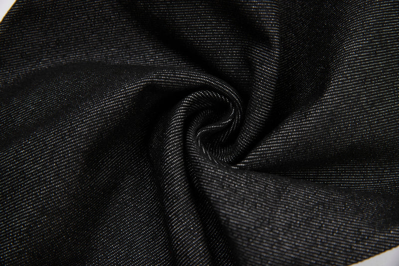Close-up of black denim fabric twisted into folds with visible twill texture