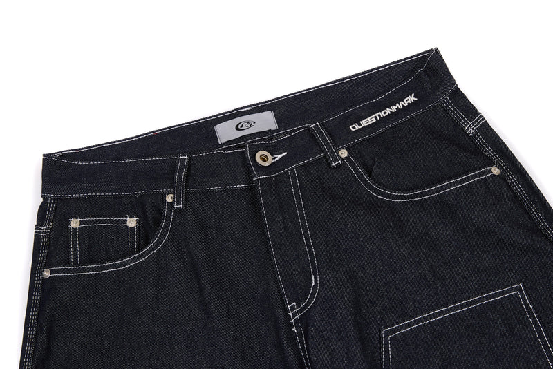 Top section of dark denim pants with belt loops, button fly, and contrast stitching