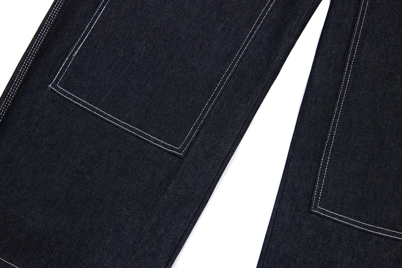 Close-up of leg panel seam on dark denim pants with contrast topstitching