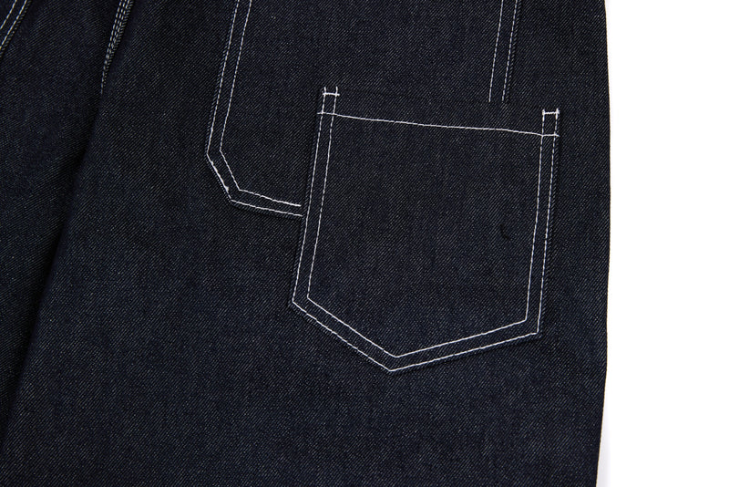 Close-up of back pocket on dark denim pants with white contrast stitching