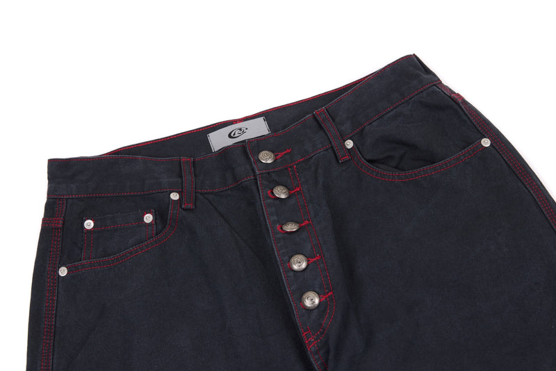 Top of dark denim pants showing waistband, button fly, and front pocket details