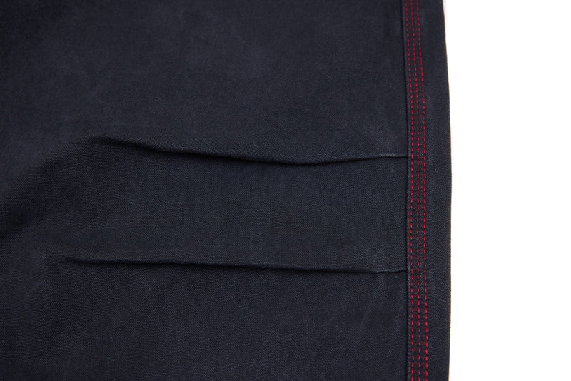 Close-up of dark denim pant leg hem with red stitched side seam