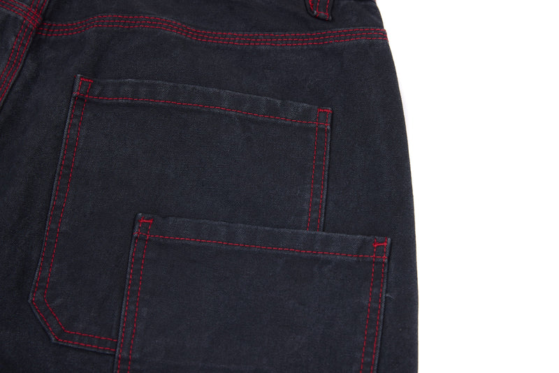 Back pocket detail on dark denim pants with red stitched seams