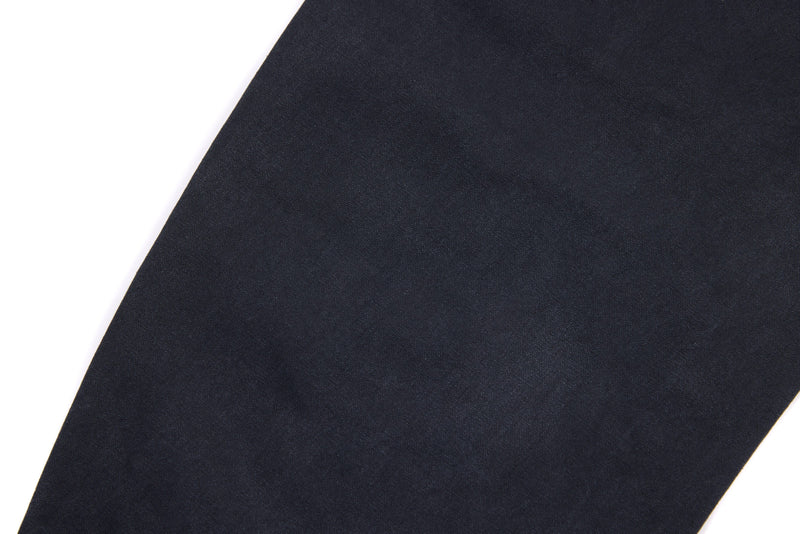 Close-up of dark denim pant leg with smooth fabric and curved side seam