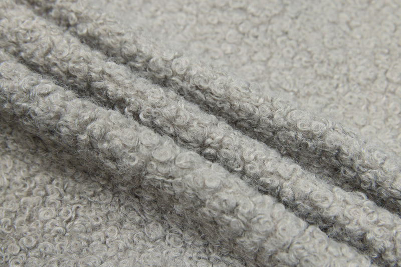 Close-up of light gray curly fleece texture with folded fabric