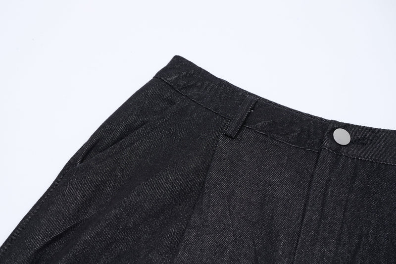 Dark denim waistband and top seam with button closure, close-up side angle