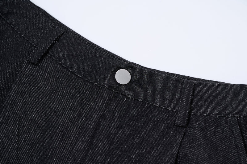 Waistband close-up of dark denim pants with silver button and belt loop