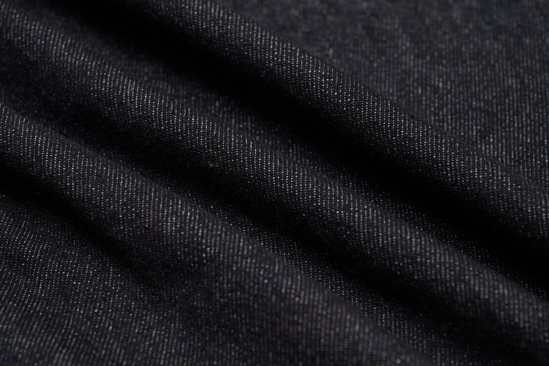 Close-up of dark denim fabric texture with visible weave and folds