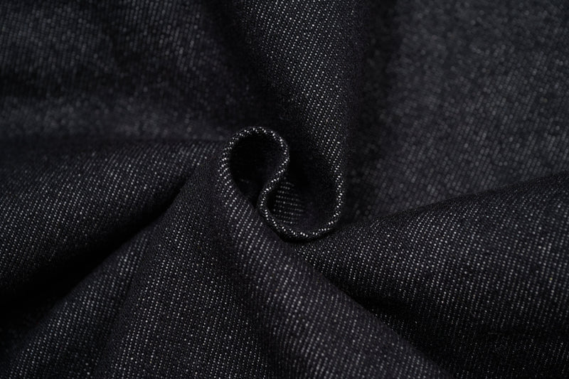 Close-up of dark denim fabric folds and stitching texture