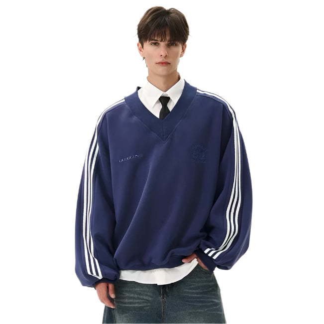Model wearing a navy blue oversized V-neck pullover sweatshirt with white contrast sleeve stripes layered over a white collar