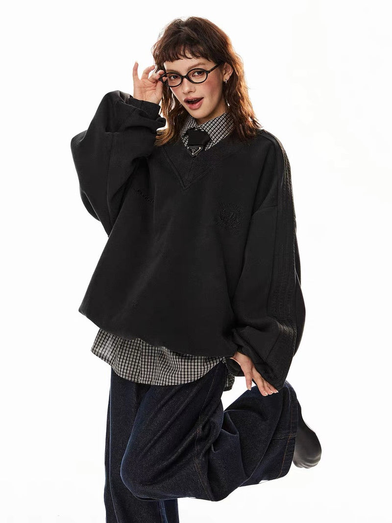 Model wearing black V-neck pullover sweatshirt with check shirt layered underneath