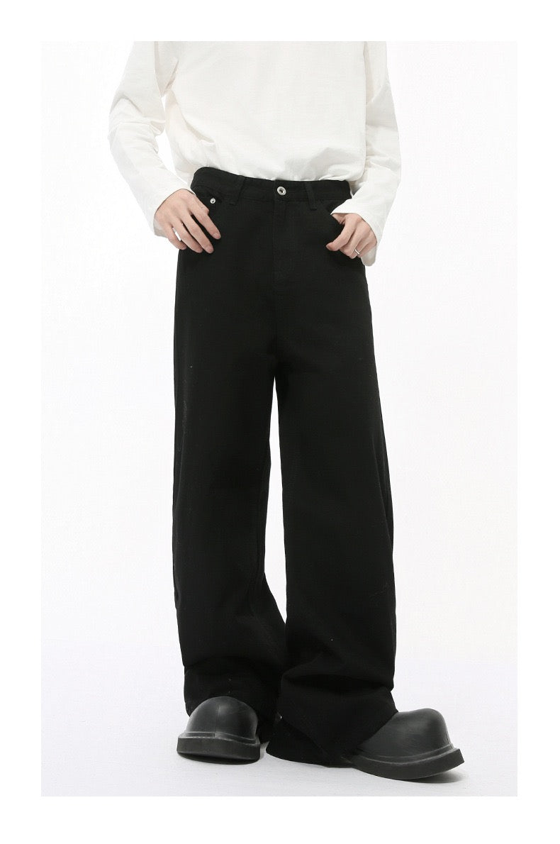 Solid black wide-leg jeans worn by model, front view with hands in pockets