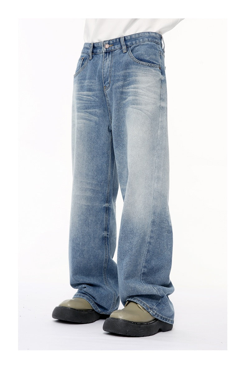 Side view of loose straight jeans in faded light blue denim with wide hems