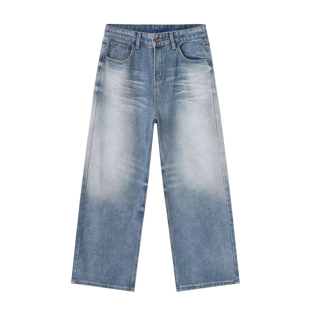 Flat lay of mid-blue wide-leg straight jeans with soft vintage fading and subtle whisker detailing