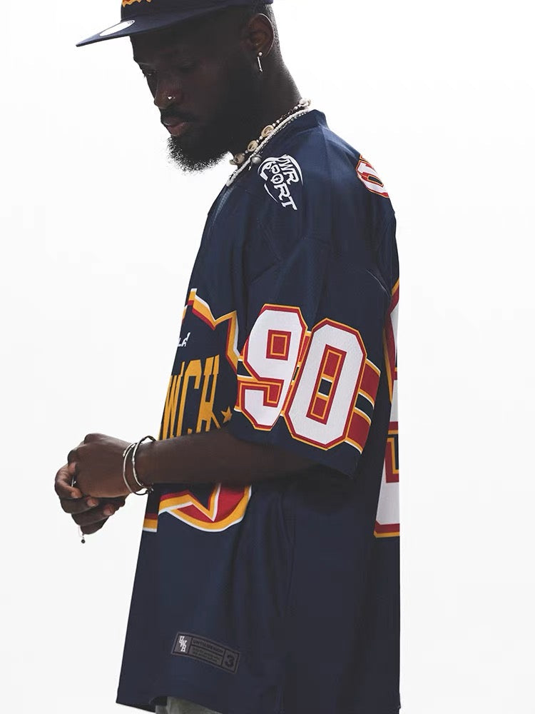 Man wearing navy mesh football jersey with bold 90 graphic and retro streetwear styling