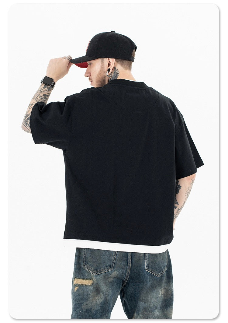 Back view of a man wearing a black oversized streetwear football tee, cap, and distressed jeans