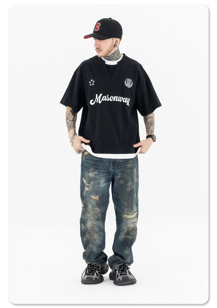 Black Masonway football tee styled with oversized fit, worn with distressed jeans and a black cap on a white background