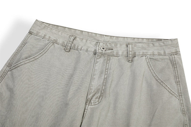 Close-up of light gray pants waistband with button closure and front pockets