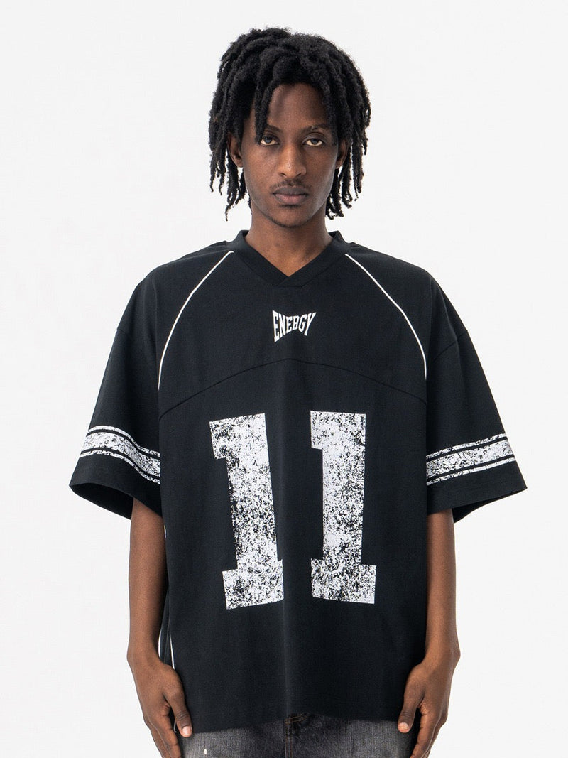 Model wearing a black oversized vintage jersey T-shirt with white trim and distressed number 11 graphic on the front
