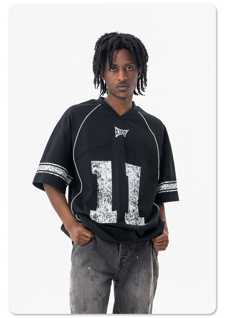 Black oversized vintage jersey T-shirt with white Energy 11 print and distressed sleeve stripes on a model against a white background