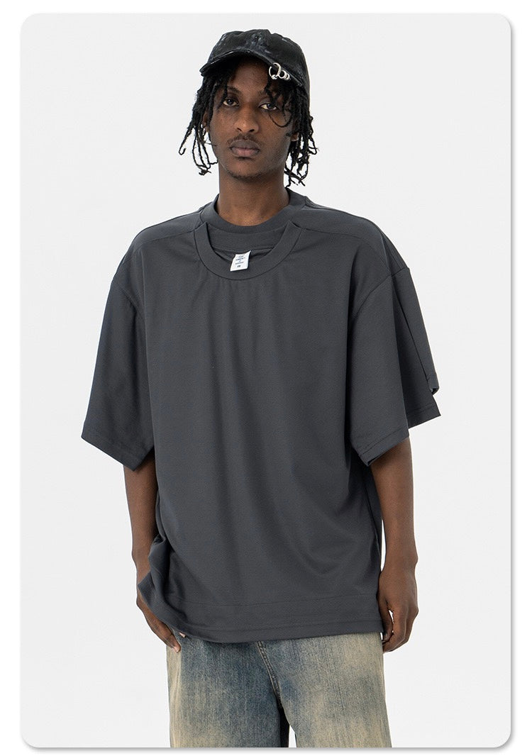 Model wearing oversized dark gray Seakoff T-shirt with layered optical illusion design and dropped shoulders
