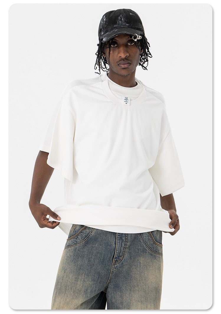 Model wearing oversized white T-shirt with dual-layer optical illusion design, paired with faded jeans and black cap