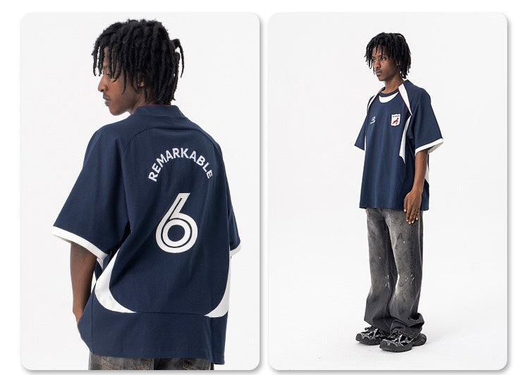 Oversized navy football jersey tee with white trim, back crest print and number 6 on a model in a studio setting