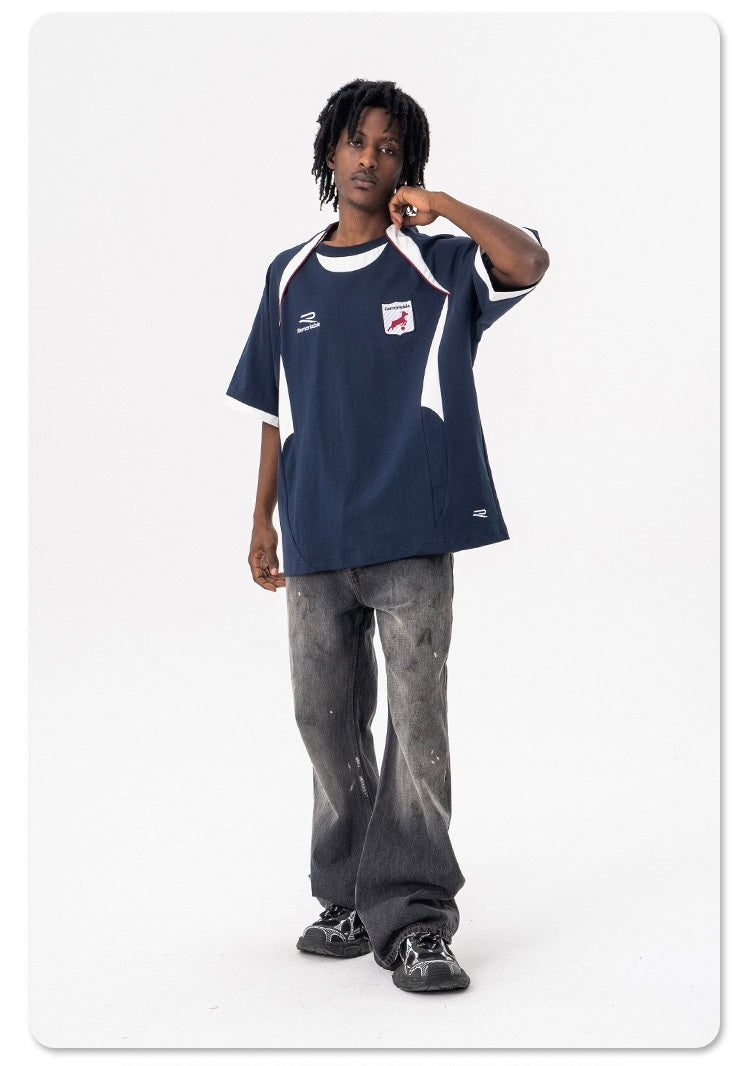 Oversized navy varsity football tee with white trim and retro crest, styled on model with baggy jeans