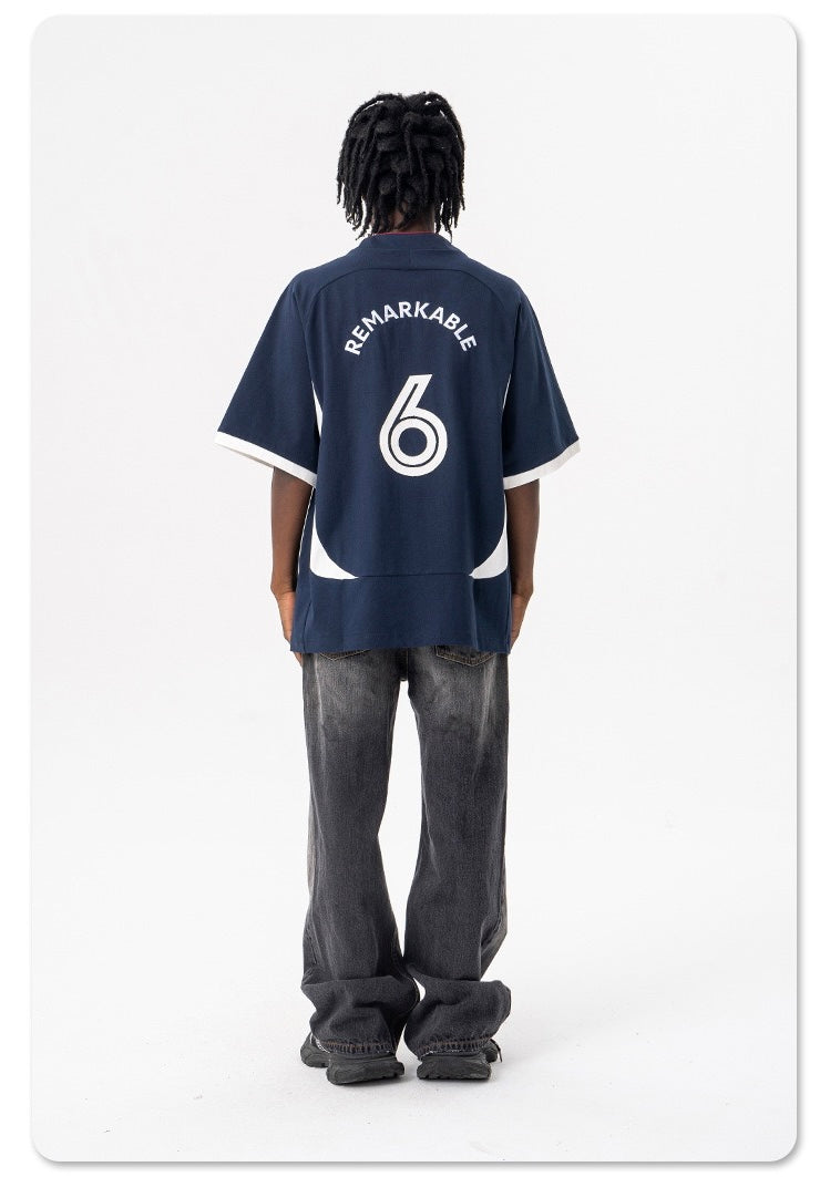 Oversized navy football jersey tee with white trim and back graphic reading Remarkable 6, worn with loose jeans