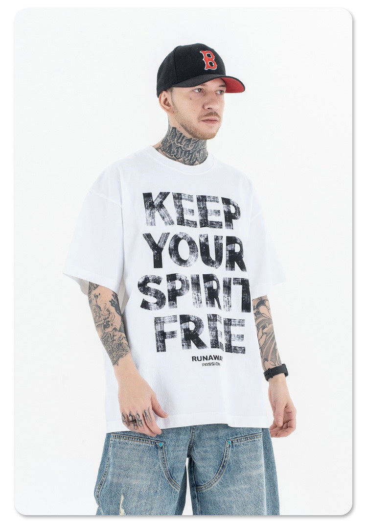 Man wearing oversized white graphic tee with bold Keep Your Spirit Free print and loose denim jeans