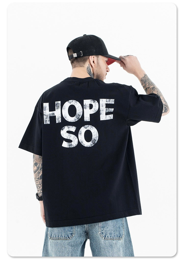 Black oversized graphic tee with distressed HOPE SO print on the back, worn with jeans and a cap