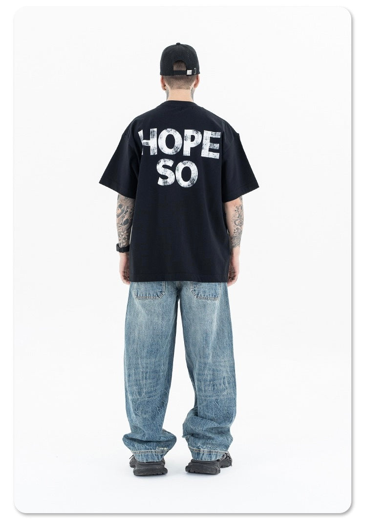 Black oversized graphic tee with HOPE SO print on the back, styled with baggy faded jeans and a cap