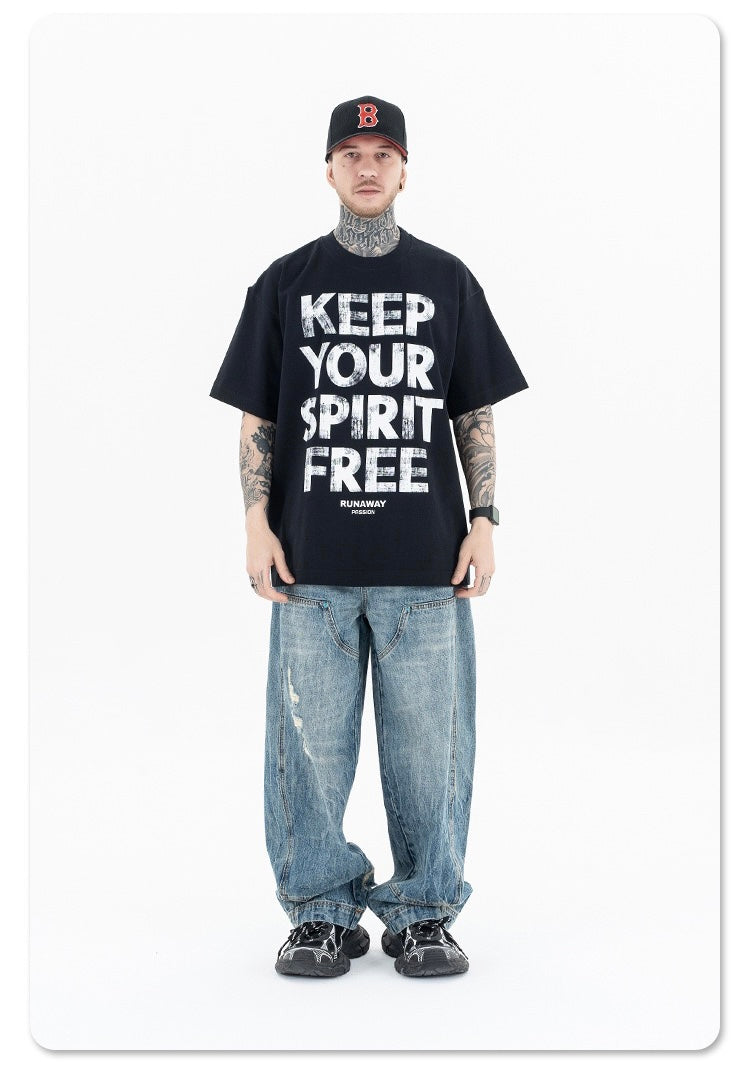 Black oversized graphic tee with bold Keep Your Spirit Free print, styled with baggy jeans and a baseball cap