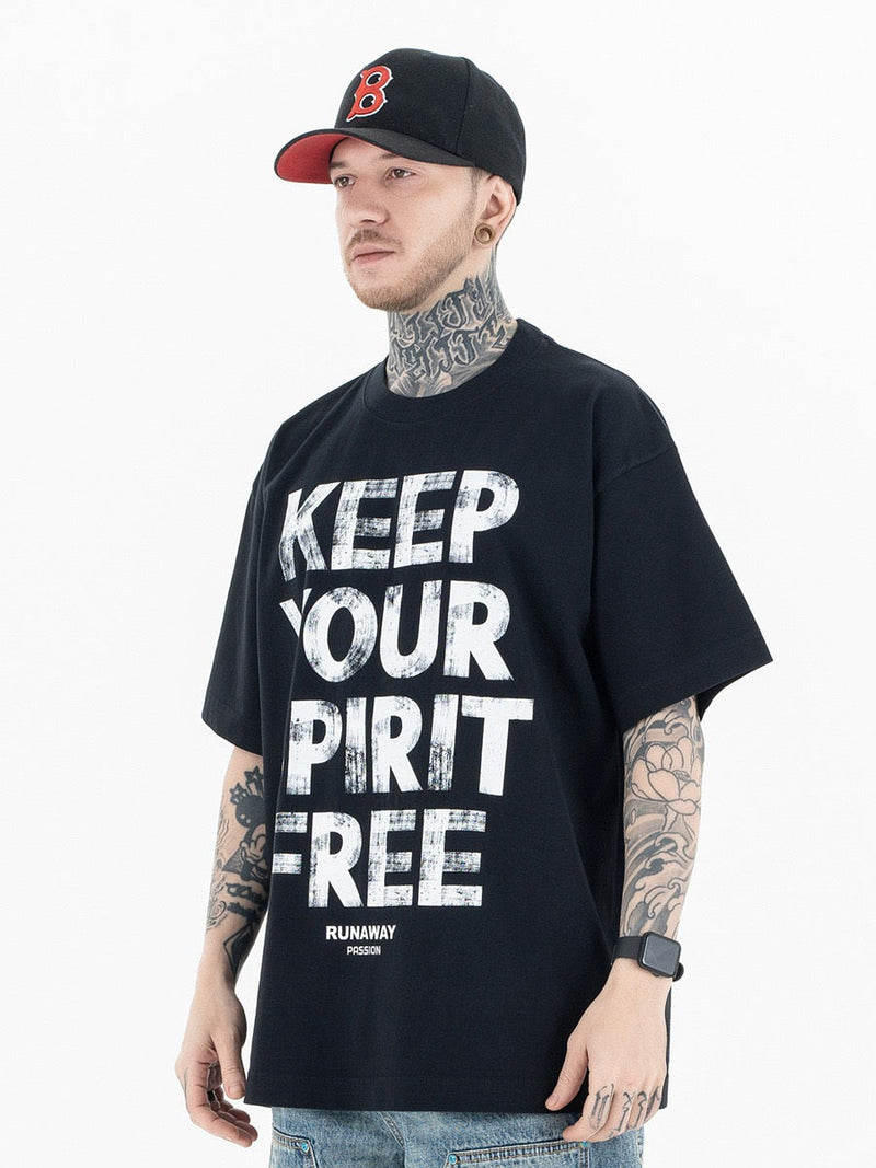 Black oversized graphic tee with bold Keep Your Spirit Free print on the front, styled on a tattooed male model