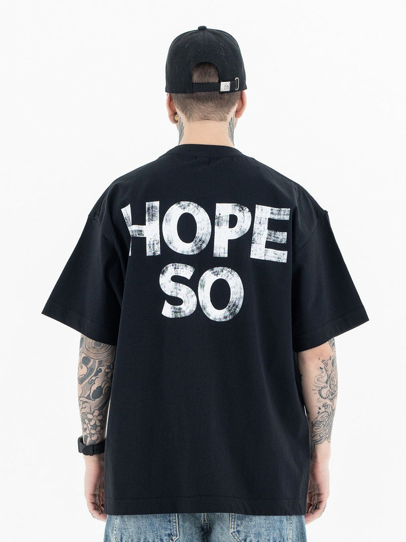 Black oversized graphic tee with bold distressed HOPE SO print on the back, worn by a tattooed model