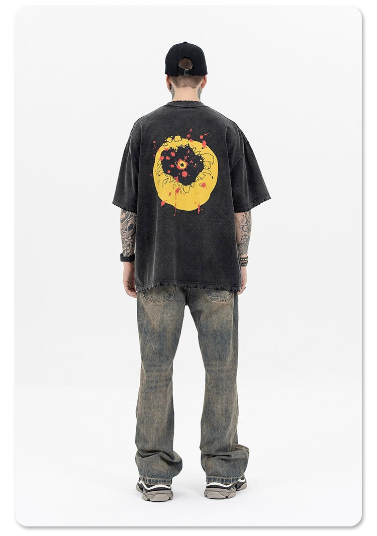 Washed black oversized tee with a distressed yellow smiley graphic on the back, worn with faded jeans and cap