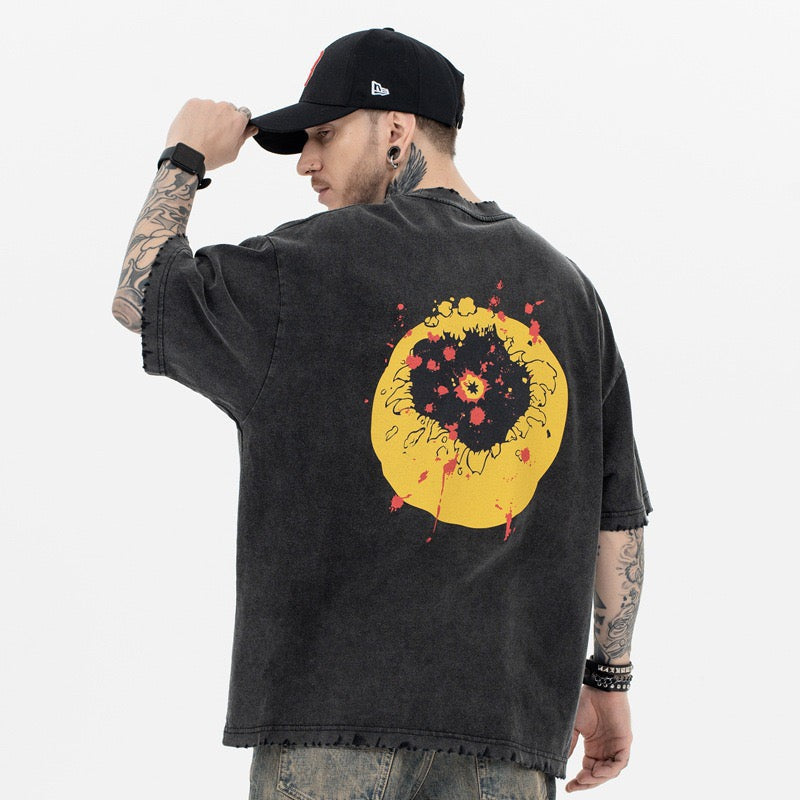 Oversized washed black tee with distressed yellow smiley graphic on the back, worn by a model in a black cap