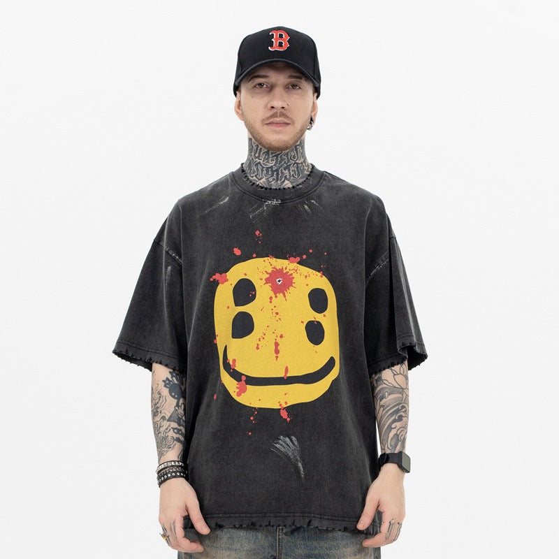 Oversized washed black graphic tee with distressed yellow smiley face and red splatter print on model