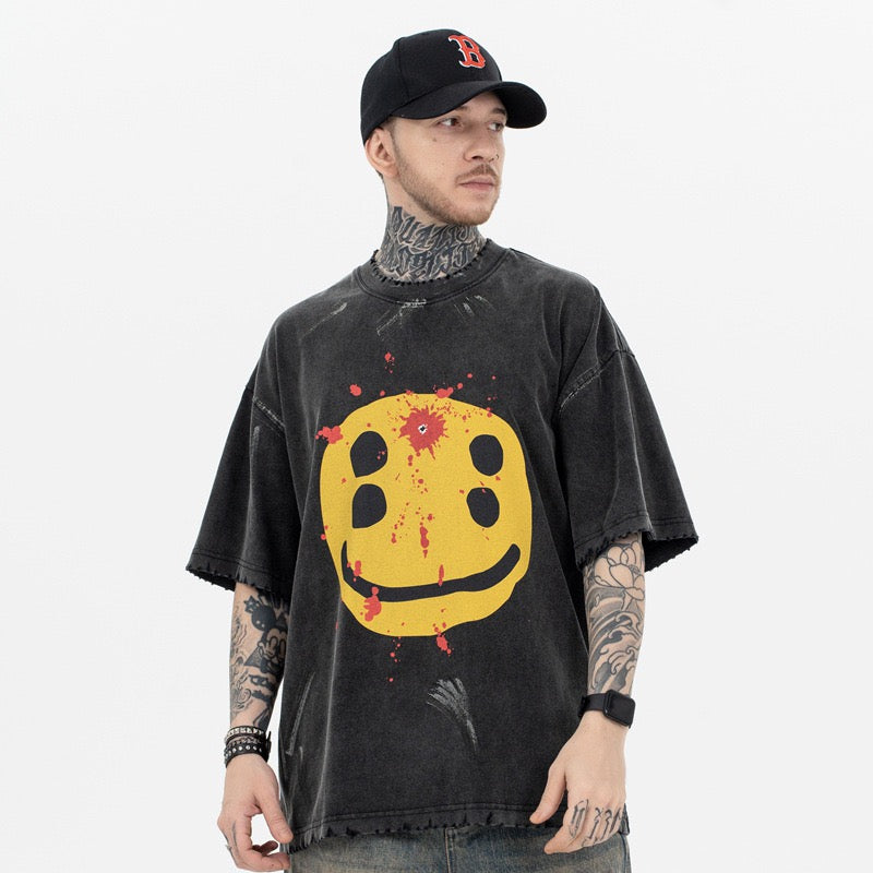 Washed black oversized graphic tee with distressed yellow smiley face and red paint splatter print on front