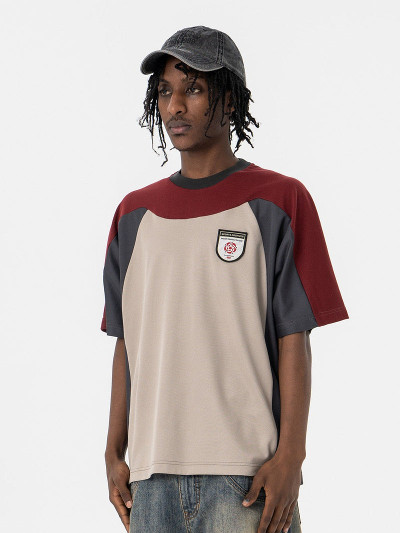 Oversized retro colorblock tee with burgundy, charcoal and beige panels, worn with jeans and a black cap