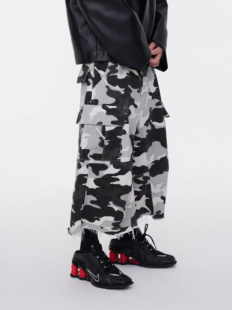 Side view of gray camo cargo shorts worn with a black jacket and black sneakers