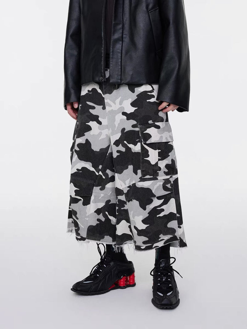 Front view of wide-leg camo cargo shorts worn with a black jacket and black sneakers
