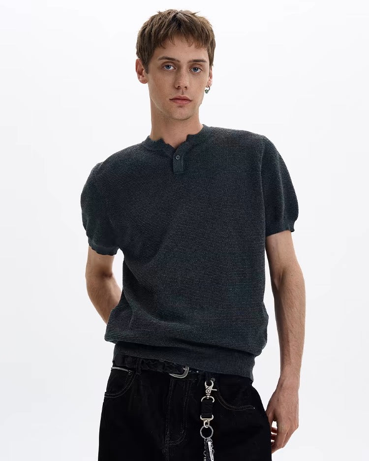 Dark textured knit short sleeve polo tee worn by a male model with a relaxed fit and split neckline